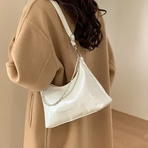Sac sous le bras minimaliste en cuir verni blanc avec chaîne, porté par un mannequin