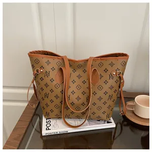 Detail view of large printed tote bag with leather handles on white books in a cozy setting