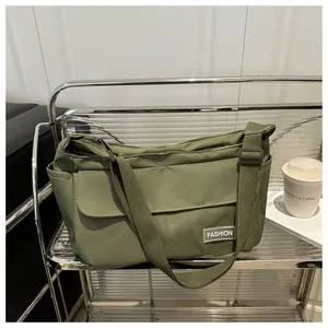 Detail of army green canvas messenger bag featuring a front pocket and fashion label