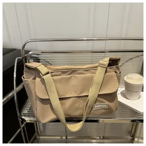 Detail of a beige nylon messenger bag showing adjustable strap and front pocket