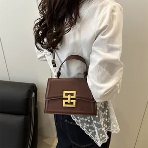 Vintage brown leather crossbody bag with a gold chain buckle shown on a model
