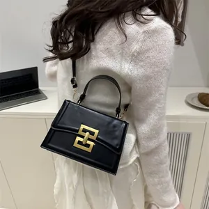 Vintage black leather crossbody bag with bold gold geometric lock and top handle
