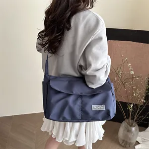 Navy blue nylon messenger bag with fashion tag worn by model in casual outfit