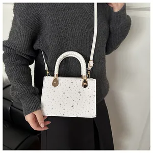 Witte crossbodytas met sterrenprint gedragen met een grijze gebreide trui