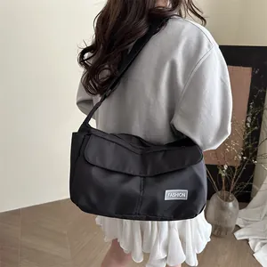 Versatile black messenger bag in nylon with adjustable strap and fashion label detail