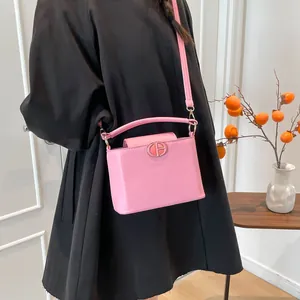 Sac seau en cuir PU rose avec boucle métallique porté par un mannequin en manteau noir