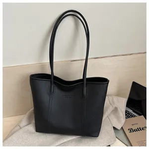 Détail du sac cabas noir en cuir grainé avec texte embossé dans un décor de style de vie