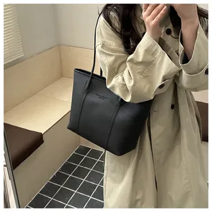 Détail du sac cabas en cuir grainé noir avec texte embossé et doubles bandoulières