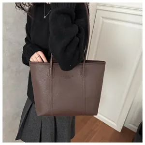 Gros plan sur la texture du cuir grainé marron foncé d'un sac cabas minimaliste chic