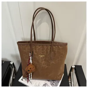 Detail of leopard print tote bag with plush bear charm on leather chair