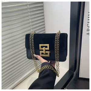 Detail der goldenen geometrischen Schnalle an der schwarzen Wildleder- und Lederhandtasche