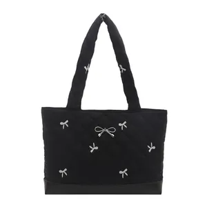 Zwarte gewatteerde tote bag met zilveren strikborduursels en metalen strikdetail