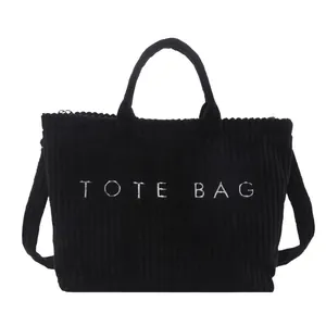 Large black corduroy tote bag with white lettering for stylish autumn commute