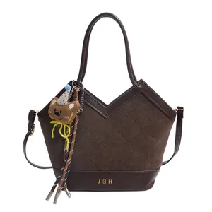 Dark brown bucket bag with diamond quilted stitching and a cute bear charm accessory