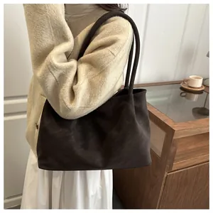 Detailopname van een donkerbruine suède shopper met matte textuur en dubbele dunne riemen