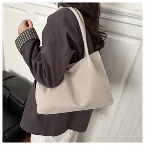 Detailopname van de beige minimalistische draagtas met matte lederen textuur en lange riemen