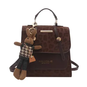 Vintage leopard print handbag with brown leather trim and a rabbit charm on white background