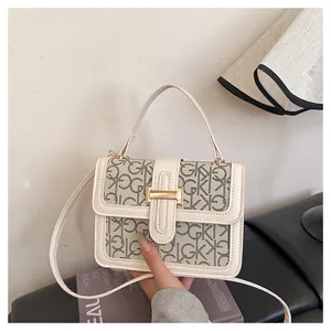 Detail of beige square bag with GK monogram pattern and gold metallic buckle closure