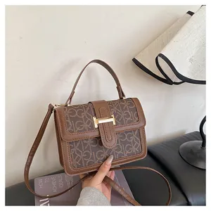 Close-up of vintage brown small square bag with GK monogram and gold H-buckle detail