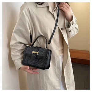 Detailed view of black leather square handbag with GK monogram pattern and gold metal buckle