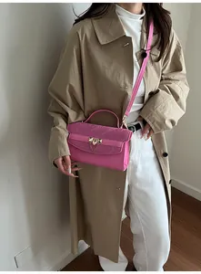 Détail d'un sac rose avec texture plissée et boucle en métal doré porté par mannequin