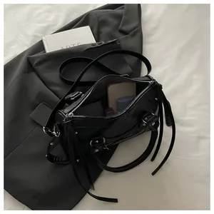 Macro detail of black studded Boston bag showing spacious interior with daily essentials
