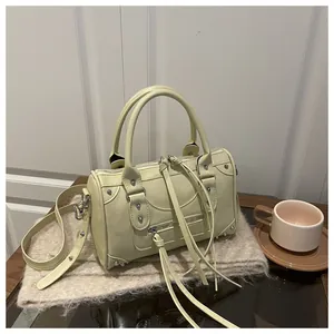 Close-up of a pale yellow Boston bag with silver studs and long leather tassels
