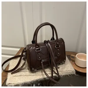 Detailed close-up of dark brown Boston bag featuring silver studs and long leather tassels