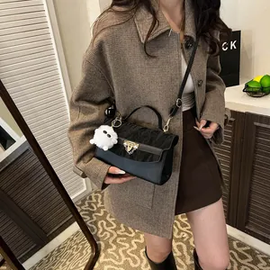 Sac bandoulière chic en patchwork noir avec fermoir doré et porte-clés peluche