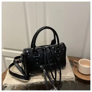 Detailed macro view of black leather Boston bag with silver studs and long leather tassels