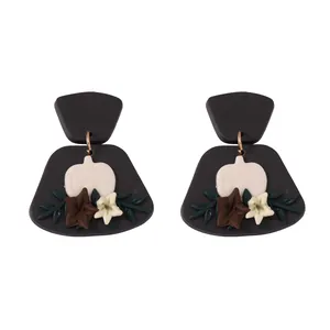 Handmade polymer clay pumpkin earrings with white flowers and gold rings on black base