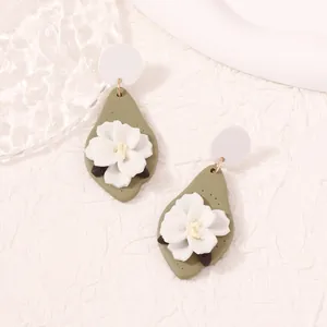 Olive green leaf-shaped clay earrings featuring 3D white floral motifs and gold accents