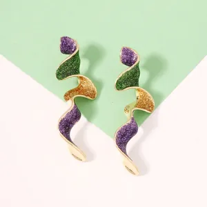 Détail de boucles d'oreilles spirales avec paillettes violettes et vertes sur métal doré