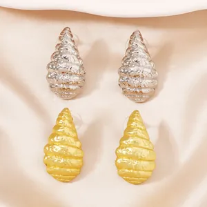 Waterdruppelvormige spiraal oorbellen in goud en zilver op roze satijnen stof