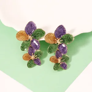 Makroaufnahme von dreischichtigen Blumenohrringen mit lila und grünem Glitzereffekt