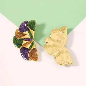 Détail de grandes boucles d'oreilles fleurs géométriques avec paillettes violettes et vertes