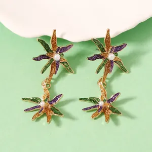 Détail de boucles d'oreilles florales avec paillettes violettes, vertes et perles