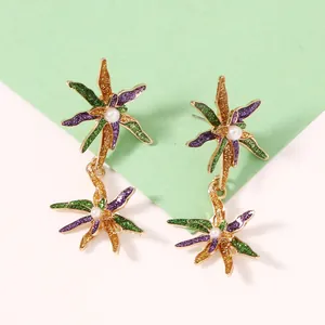 Détail des boucles d'oreilles fleurs Mardi Gras avec paillettes violet vert or et perles