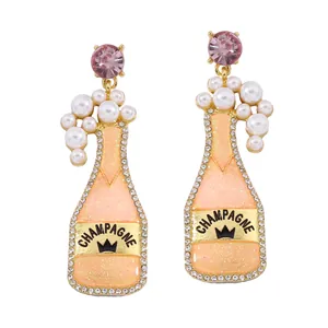 Detailed view of champagne bottle earrings with pink glitter, pearls, and crystals