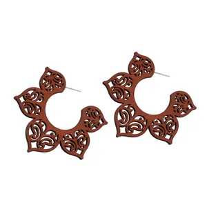 Gros plan de grandes boucles d'oreilles en bois en forme de C avec motifs évidés