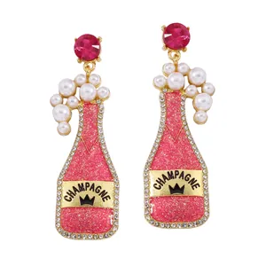 Detail of pink resin champagne bottle earrings with white pearls and sparkling crystals