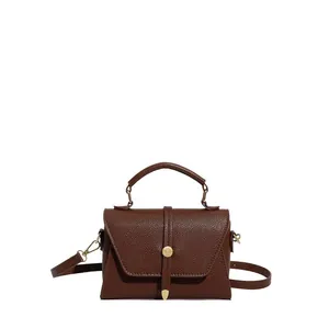 Dark brown pebble leather crossbody handbag with top handle and gold circular buckle