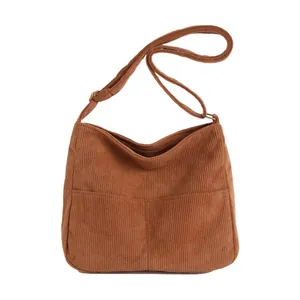 Brown corduroy tote bag with dual front pockets and adjustable shoulder strap on white backdrop