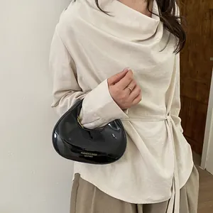 Minimalist black glossy crescent handbag for women shown with a stylish casual outfit