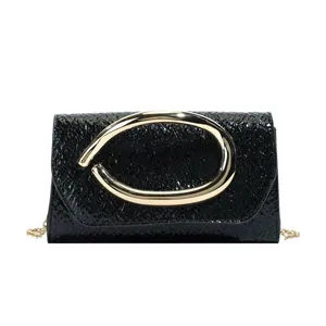 Minimalist black crinkle patent leather crossbody bag with a bold gold oval buckle