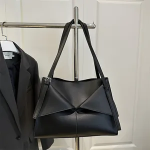 Minimalist black leather underarm tote bag with unique triangular overlap design