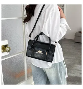 Detail of black crocodile texture handbag with gold heart buckle and crossbody strap