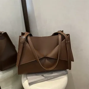 Minimalist brown rectangular underarm bag with geometric folding and adjustable straps
