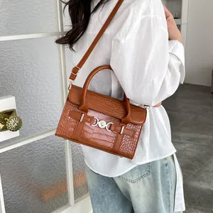 Brown crocodile embossed leather crossbody bag with metal ring buckle shown on a model