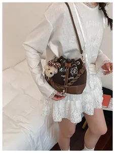 Detail of dark brown bucket bag with white cat print and cute plush bear charm